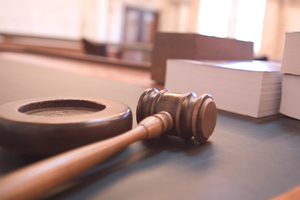 Wooden gavel and sound block on a courtroom table with stacked documents, shallow depth of field