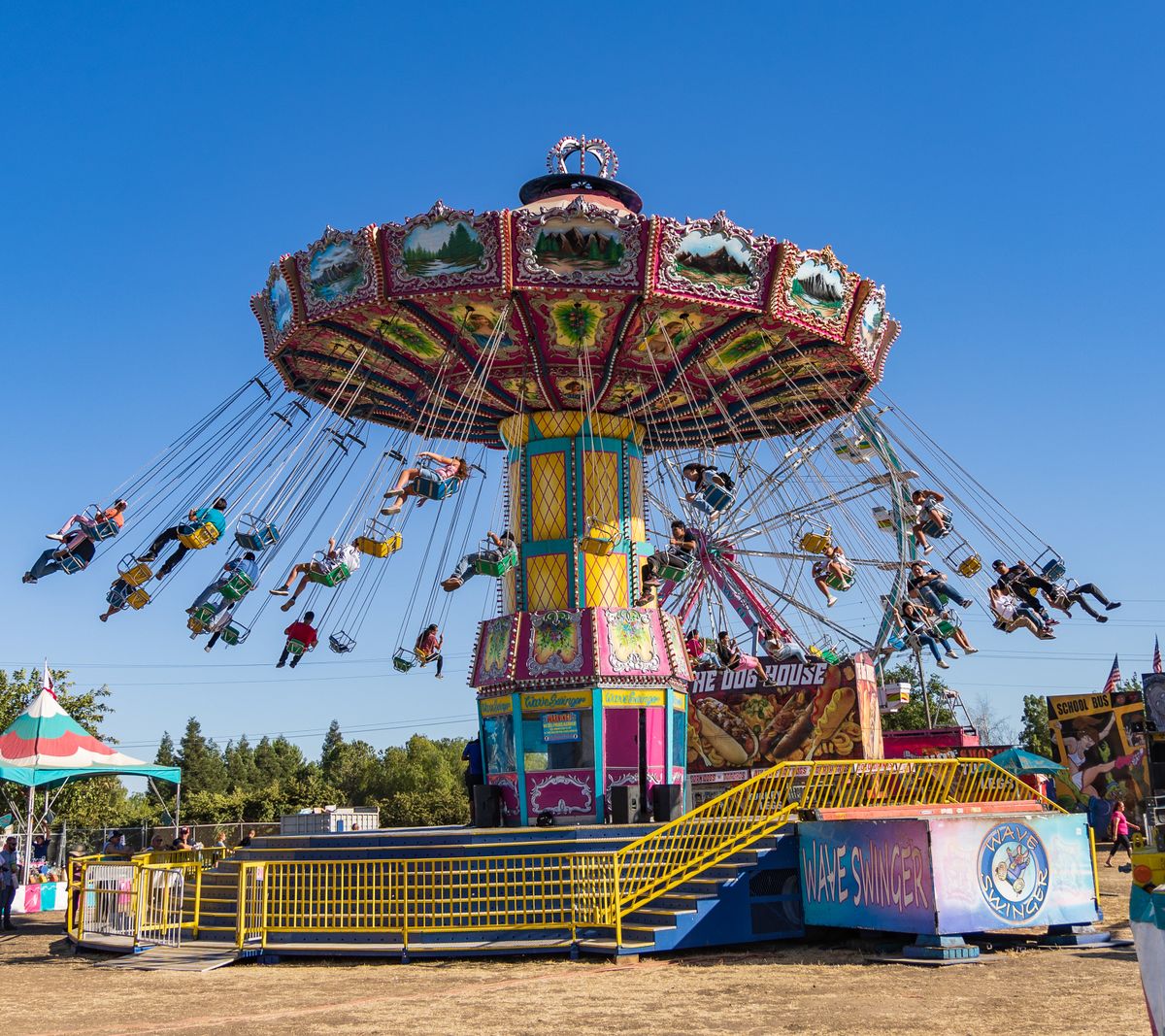 Wave Swinger ride at a county fair midway on a clear day, general festive fairgrounds atmosphere