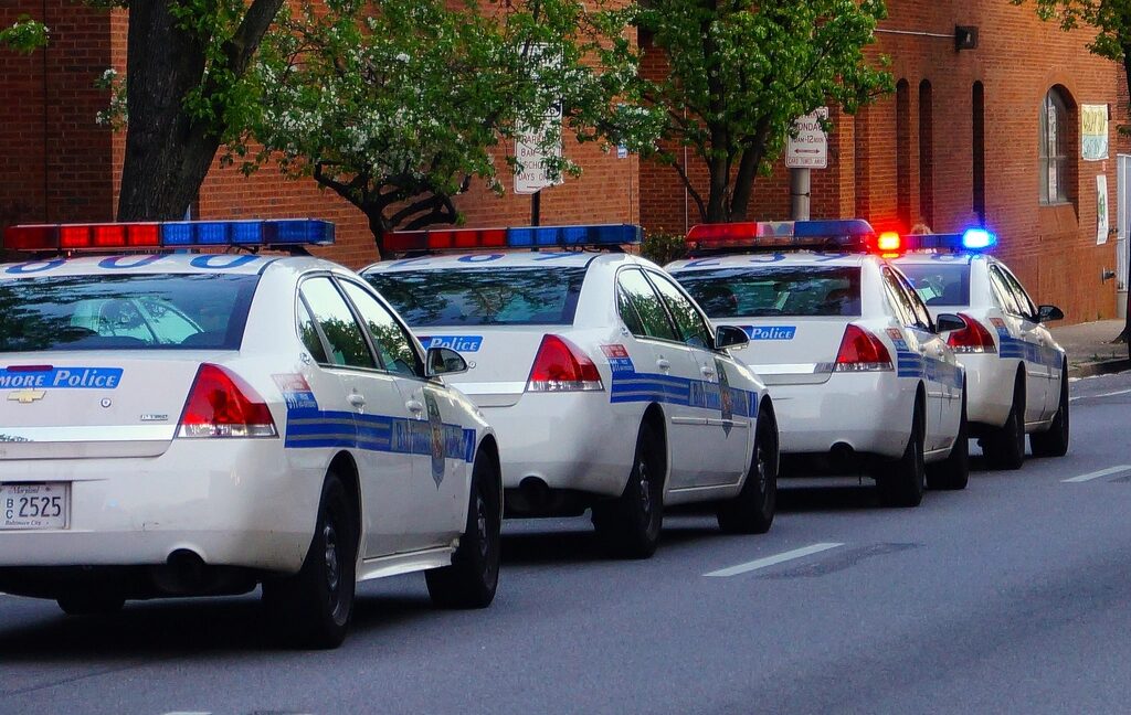 Police cruisers with lights on parked along a city street