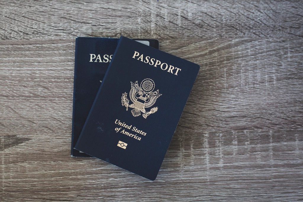 Two U.S. passports overlapping on a rustic wooden table